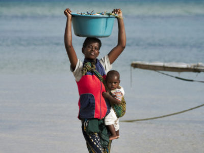 African woman with baby carrying a bucket filled with crab on her head. Coast of Benguerra Island. Mozambique. (c) Martin Harvey / WWF